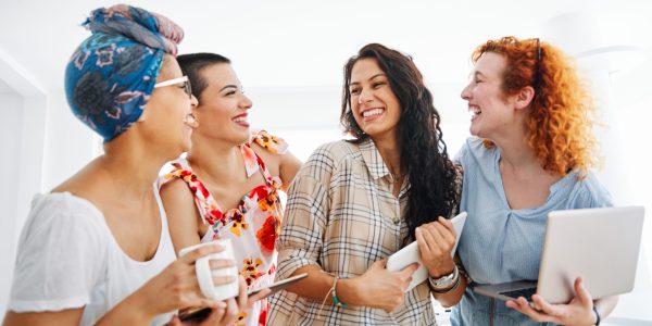 Happy young woman girls friends with tablet and laptop in the office
